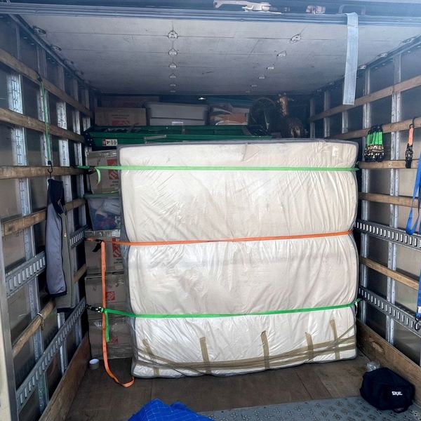 Wrapped mattresses strapped to the E-track rail on the truck wall